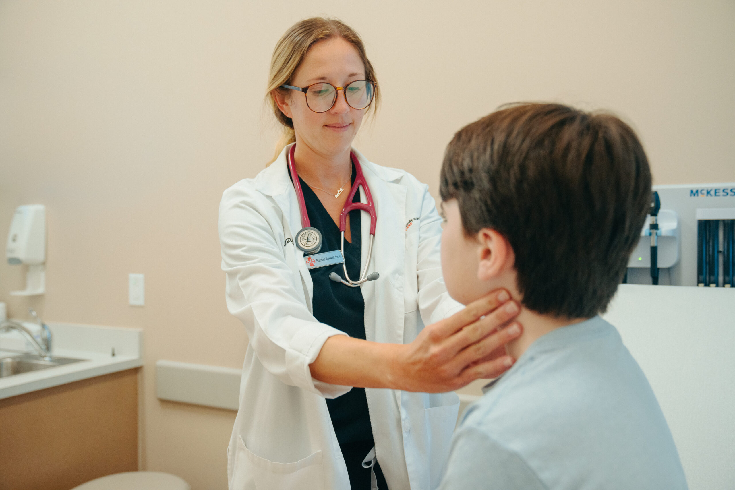 Female provider checks young boy patient's lymph nodes